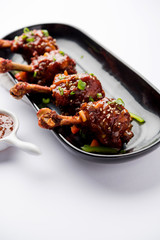 Szechuan Chicken which is a popular Indo-Chinese non vegetarian recipe. served in a plate with chilli sauce. selective focus