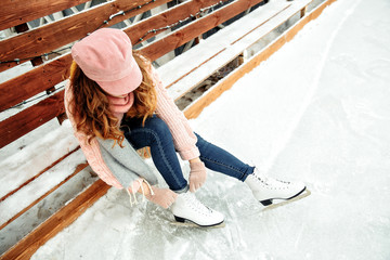 Woman tie shoelaces at figure skates at ice rink close-up, ice skating