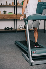 Fototapeta premium cropped view of man exercising on treadmill in living room