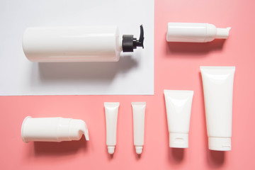 Cosmetic products collection. Blank cosmetic bottle/tube on pink and white background. Branding...