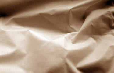 Crumpled transparent plastic surface in brown color.