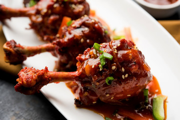 Szechuan Chicken which is a popular Indo-Chinese non vegetarian recipe. served in a plate with chilli sauce. selective focus