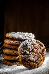a stack of cookies dusted with icing sugar on a dark background