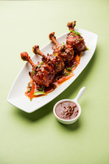 Szechuan Chicken which is a popular Indo-Chinese non vegetarian recipe. served in a plate with chilli sauce. selective focus