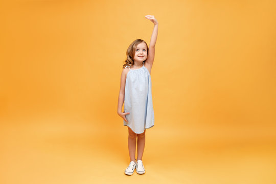 A little child measures her height on a yellow background. Concept of development, goal, success
