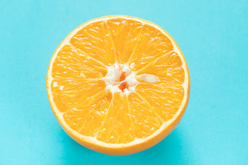 One half of juicy ripe orange on turquoise background.