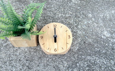 The clock is located on the floor. Needle pointed at number 6.Green leaves on the floor.Do not focus on the object.