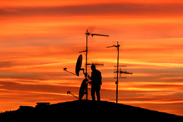 Antennista, parabole e antenne al tramonto.