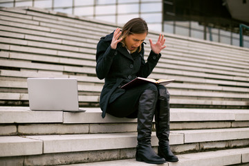 Businesswoman in panic looking at personal organizer  while working outdoor.