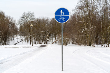 Sign of a bike path and a pedestrian in winter