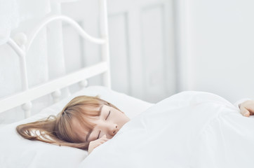 On the bed in the white room.Beautiful woman sleeping in the bedroom.Asian girl sleep well.Sleeping in a white room makes you feel comfortable.Warm tone.