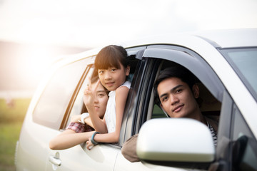 Fototapeta premium Happy little girl with asian family sitting in the car for enjoying road trip and summer vacation in camper van