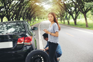 Asian woman using mobile phone while looking and Stressed man sitting after a car breakdown on street