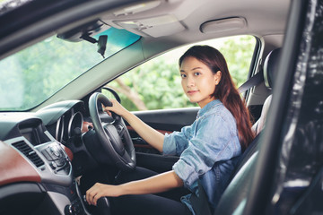 Fototapeta na wymiar Beautiful Asian woman smiling and enjoying driving a car and hand is about to drive into gear on road for travel