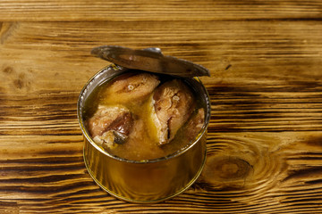 Open tin can of sardine fish on wooden table