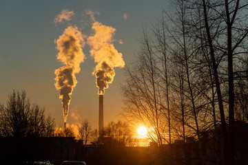 Fototapeta premium Beautiful sunset sky and smoking factory chimneys. The environmental problem of pollution of the environment and air in large cities.
