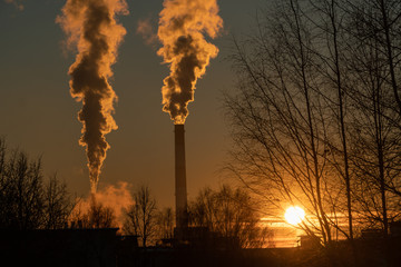 The standard problem of pollution of the environment and air. Smoky factory pipes with acrid smoke at sunset