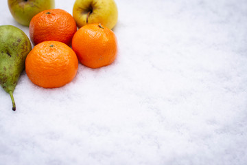 Fruits on the snow, mandarines, apples, pear