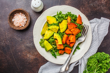 Healthy green kale salad with avocado and baked sweet potatoes. Plant based diet concept, detox...