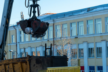 Excavator manipulator cleans the city streets from trees that interfered with power lines