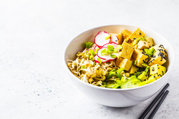 Vegan poke bowl with pickled tofu, vegetables and rice in a white bowl.