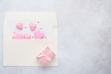 Pink heart shaped cookies in an envelope and a gift box.