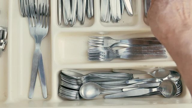 a man opens a drawer and takes some silverware