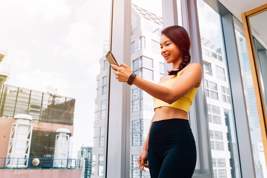 Portrait of young fit woman using smartphone at high rise gym. Female fitness model image