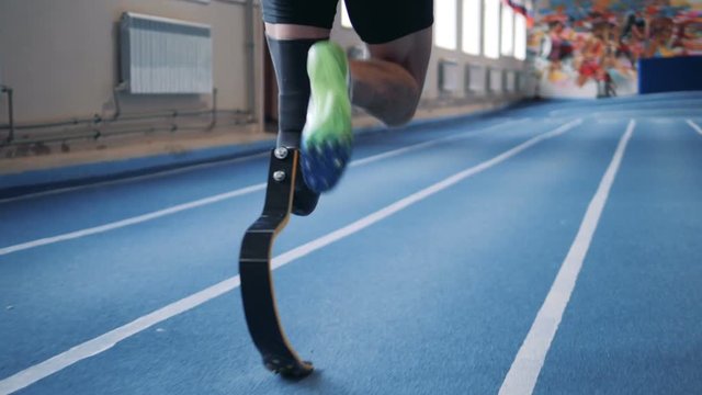 A man jogging on a track with prosthetic leg, close up.