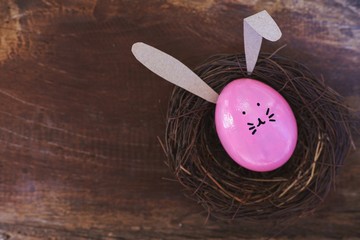 Easter egg painted into bunny face with long and fold ear in nest, Easter holiday concept