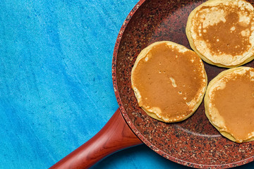 Ruddy and lush pancakes on a stone pan. Granite pan with baking on blue background