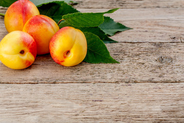 Group of ripe and sweet nectarines with fresh green leaves on wooden garden table, copy space for text