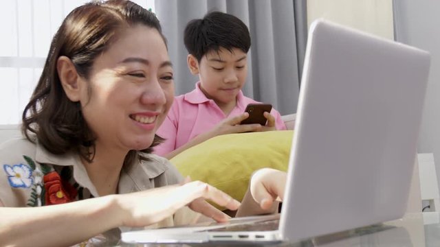 4K Family lifestyle is playing computer games. Asian Mother and son watching on laptop computer with smile face.
