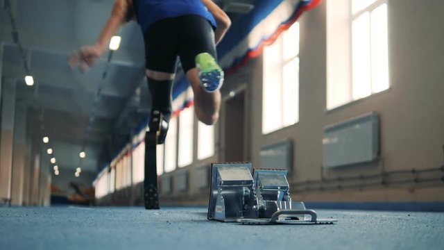 Jogger starts to sprint, wearing bionic leg, back view.
