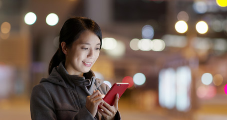 Woman use of mobile phone in the street at night