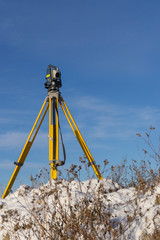 Surveyor conducts a topographical survey in winter for cadastral work at a construction site