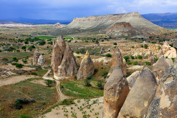 Cone-shaped tops of rocks and breathtaking contrasting valley landscape in Cappadocia