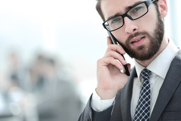 businessman talking on smartphone on office background