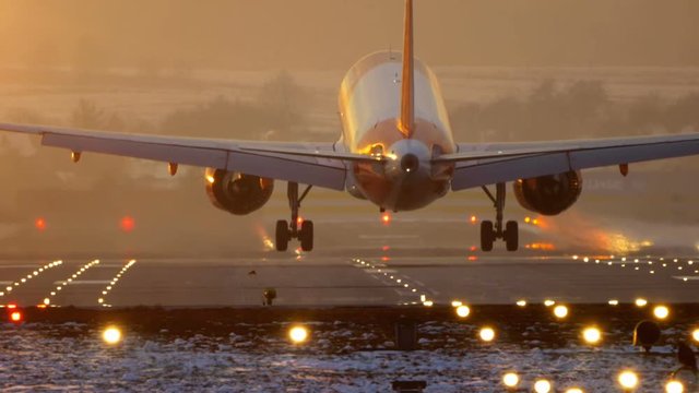 Commercial Jet Airplane Landing in airport runway at sunset in Winter. Slow Pan.