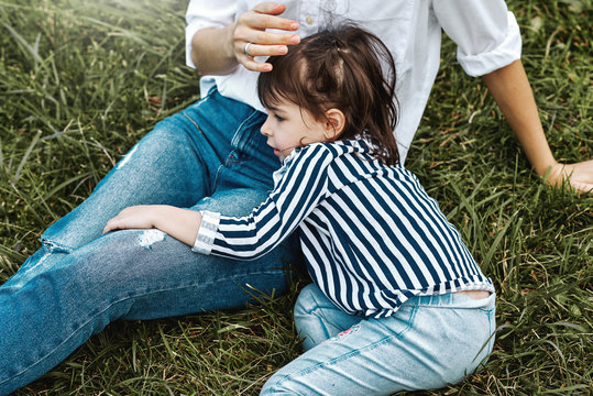 Cropped horizontal image of beautiful woman playing with her cute little girl on the green grass outdoors. Happy child and mother spend time together in the park. Mother's day concept