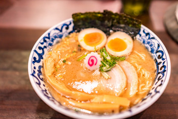 Japanese ramen soup with chicken, egg, chives and sprout on dark wooden background