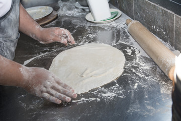 Hands preparing a pizza in the kitchen