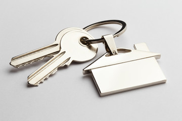 House keys with house shaped keychain on grey background