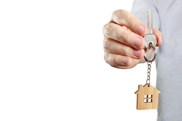 Hand holding a house key, isolated on white background