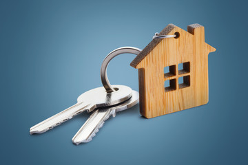 House keys with house shaped keychain on blue background