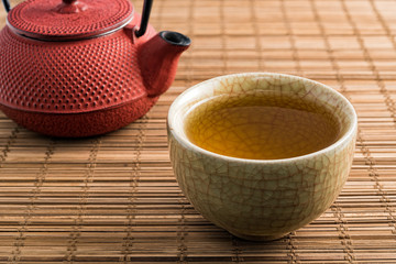 Cup of tea and japanese traditional style red teapot on natural matting