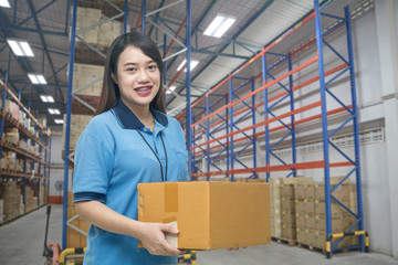 Pretty worker carrying box in the warehouse (ฺBlur background) ,Professional asian delivery woman...