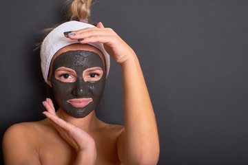 Charming young woman with cosmetic black mask on face