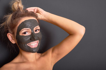 Delightful woman with a rejuvenating clay mask on her face
