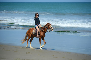 Woman riding on a horse along the ocean shore